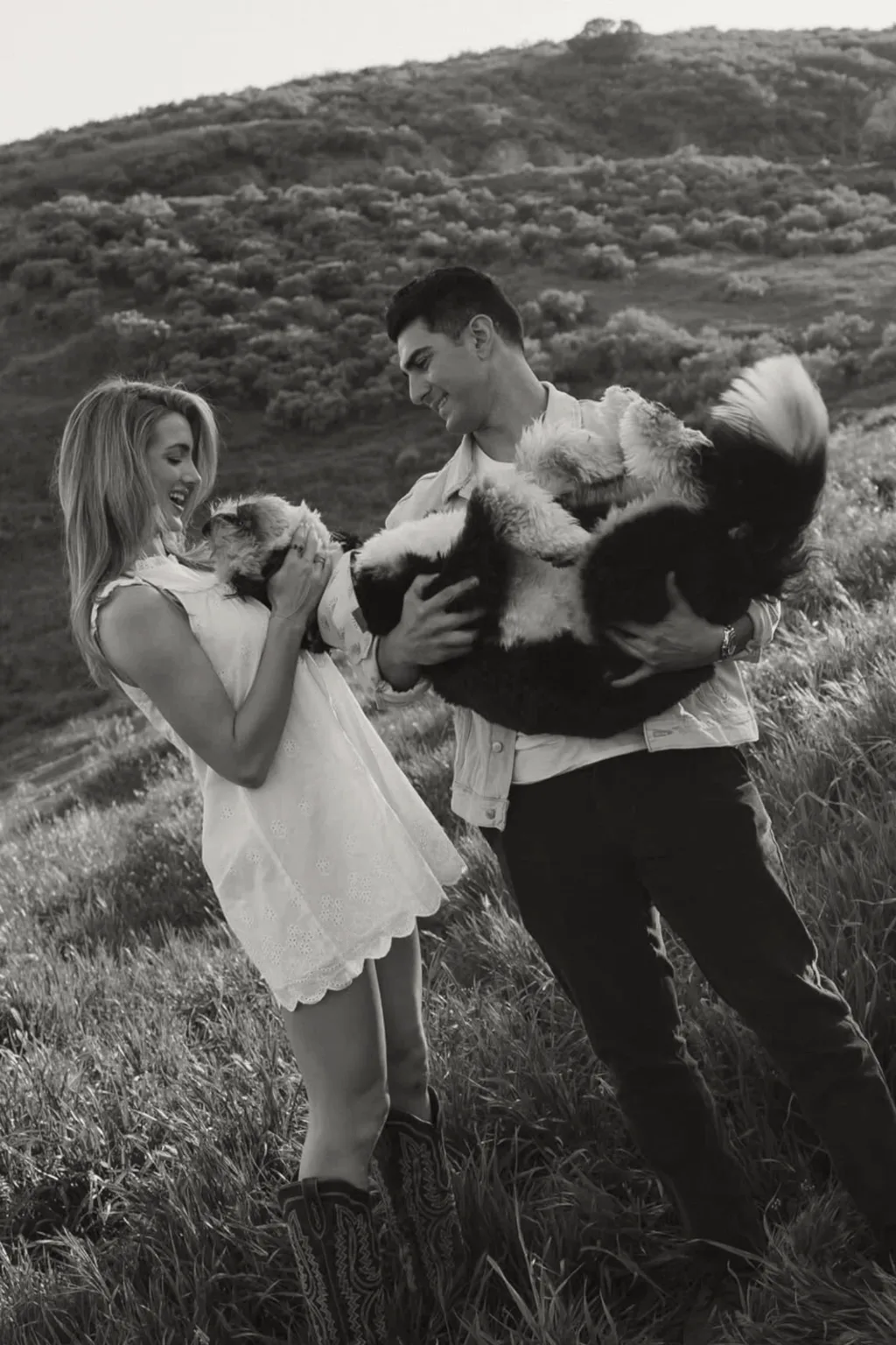 Nima and Lucy, the couple behind ARYA, laughing as they hold their dog on a California hillside.